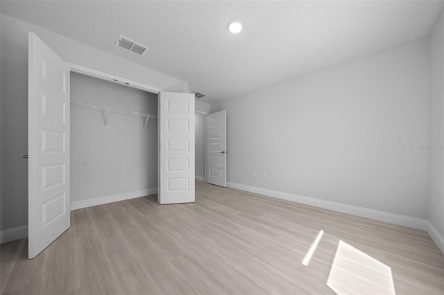 unfurnished bedroom with a closet, visible vents, light wood-style flooring, and baseboards