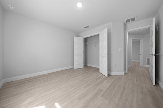 unfurnished bedroom with light wood-style floors, visible vents, and a closet