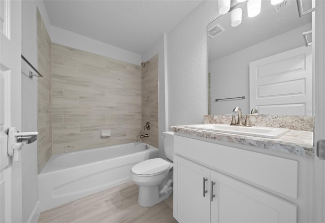 bathroom with visible vents, a textured wall, toilet, bathing tub / shower combination, and vanity