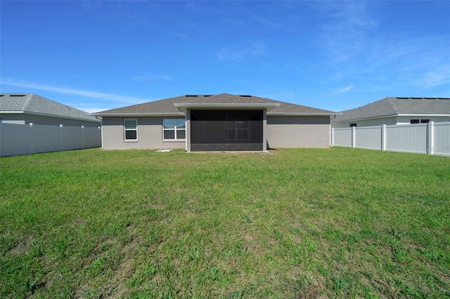 rear view of property with a sunroom, a fenced backyard, a lawn, and stucco siding