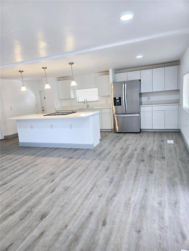 kitchen featuring light wood finished floors, light countertops, white cabinets, a sink, and stainless steel fridge with ice dispenser