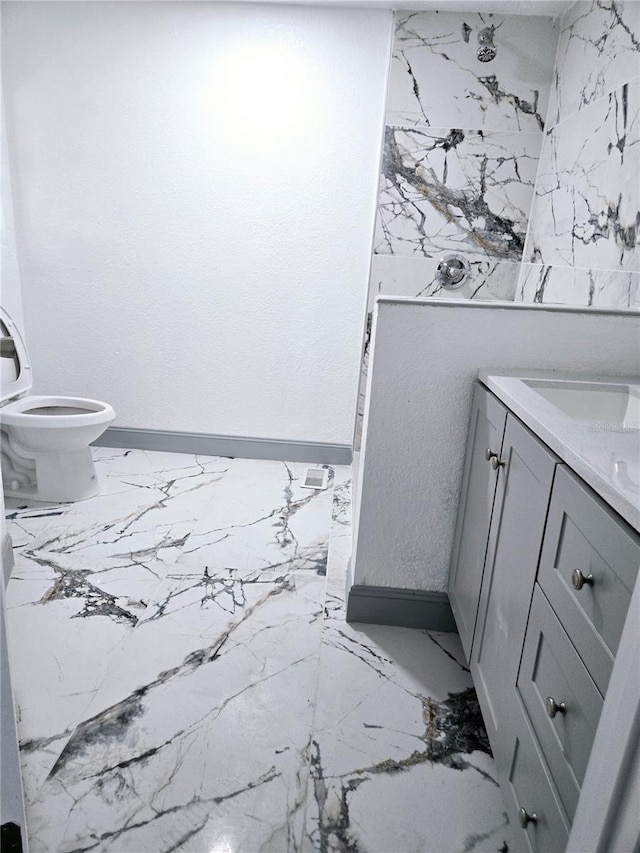 bathroom featuring toilet, marble finish floor, baseboards, and vanity