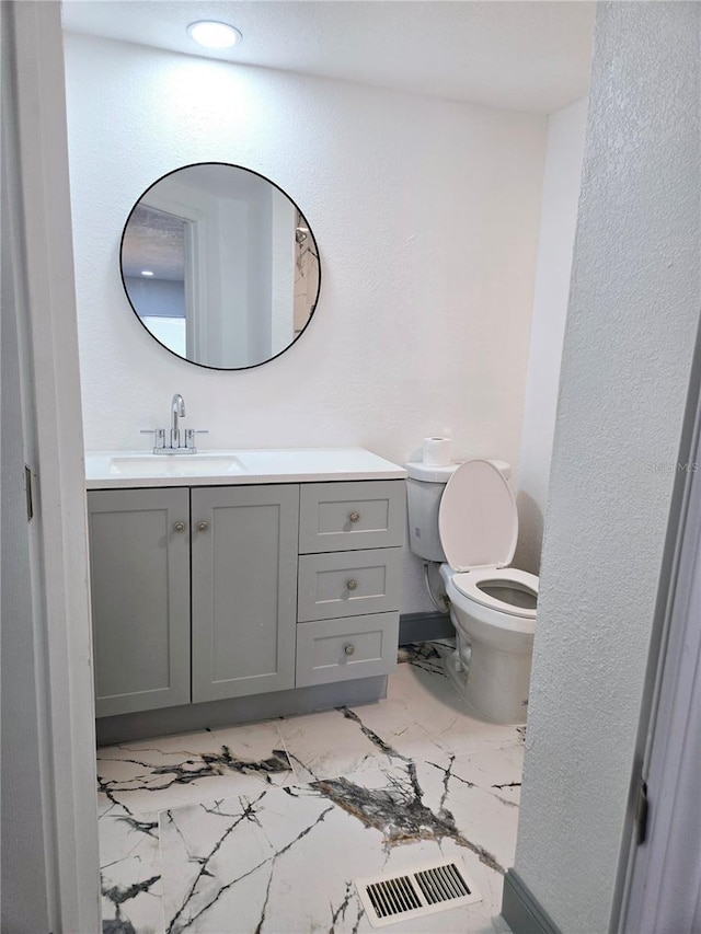 bathroom with toilet, marble finish floor, visible vents, and vanity