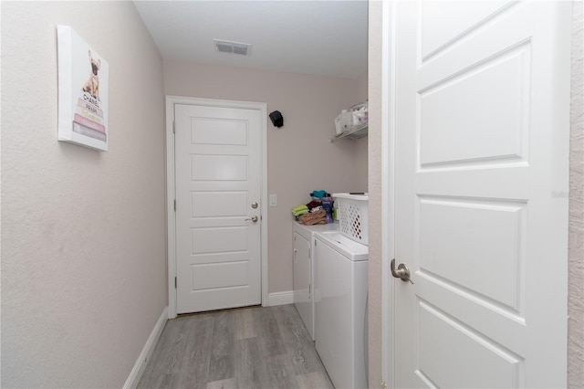 washroom with laundry area, light wood finished floors, separate washer and dryer, baseboards, and visible vents
