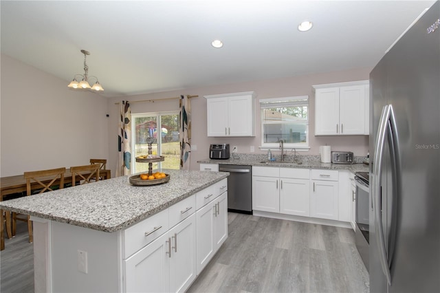kitchen with light wood-style floors, plenty of natural light, a center island, a sink, and stainless steel appliances