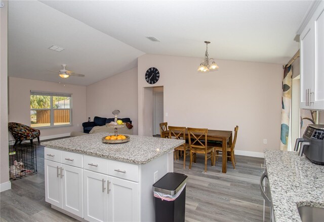 kitchen featuring white cabinetry, baseboards, lofted ceiling, and light wood finished floors