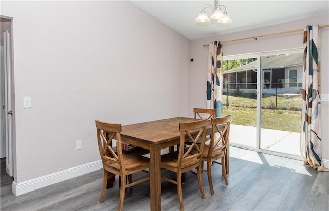 dining space featuring baseboards, wood finished floors, and a notable chandelier