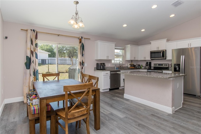 kitchen featuring a kitchen island, visible vents, wood finished floors, stainless steel appliances, and white cabinetry