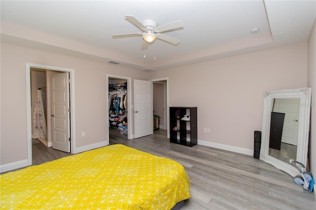 bedroom with visible vents, baseboards, a walk in closet, and wood finished floors