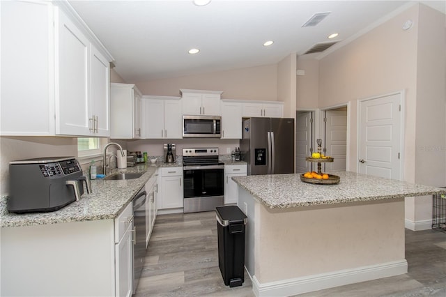 kitchen featuring a sink, light wood finished floors, appliances with stainless steel finishes, and white cabinetry