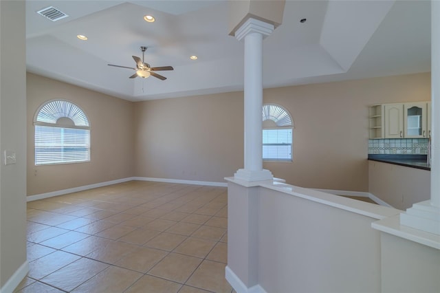 spare room featuring light tile patterned floors, visible vents, a raised ceiling, ceiling fan, and ornate columns