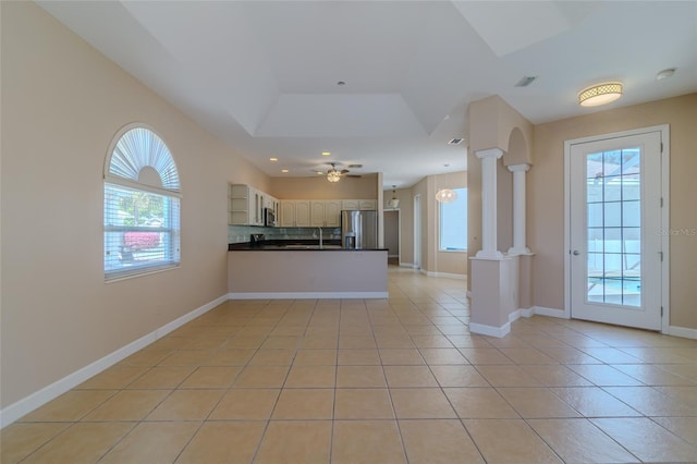 kitchen featuring dark countertops, appliances with stainless steel finishes, a peninsula, ornate columns, and light tile patterned flooring