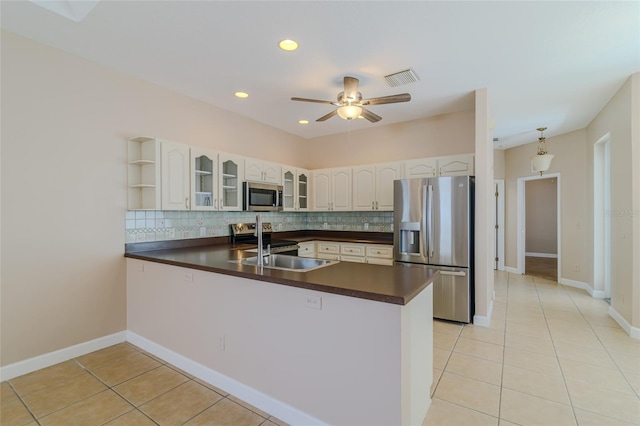 kitchen featuring a peninsula, appliances with stainless steel finishes, dark countertops, and decorative backsplash