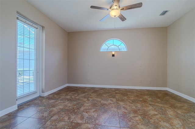 empty room featuring ceiling fan, visible vents, and baseboards