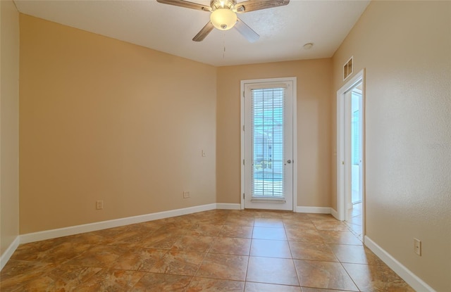 empty room featuring ceiling fan, light tile patterned floors, visible vents, and baseboards