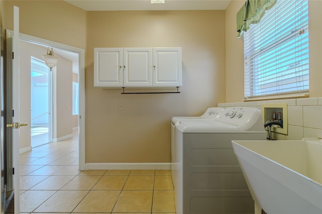 laundry room with cabinet space, baseboards, separate washer and dryer, a sink, and light tile patterned flooring