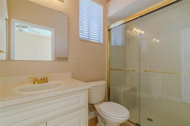 bathroom with ceiling fan, vanity, a shower stall, and toilet