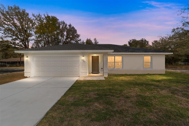 ranch-style house featuring an attached garage, concrete driveway, a front yard, and stucco siding