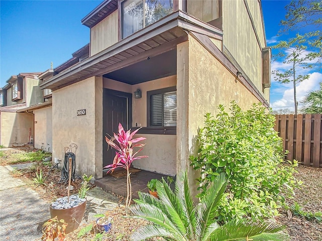 doorway to property featuring fence and stucco siding