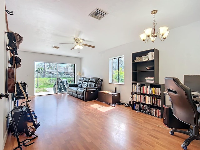 office with a healthy amount of sunlight, visible vents, wood finished floors, and ceiling fan with notable chandelier