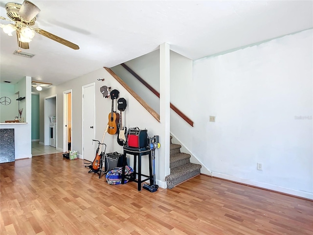 interior space with baseboards, ceiling fan, visible vents, and wood finished floors