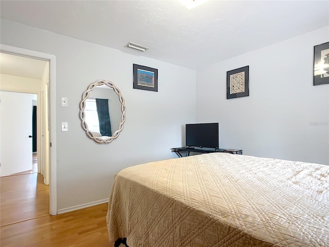 bedroom with light wood-style floors, visible vents, and baseboards