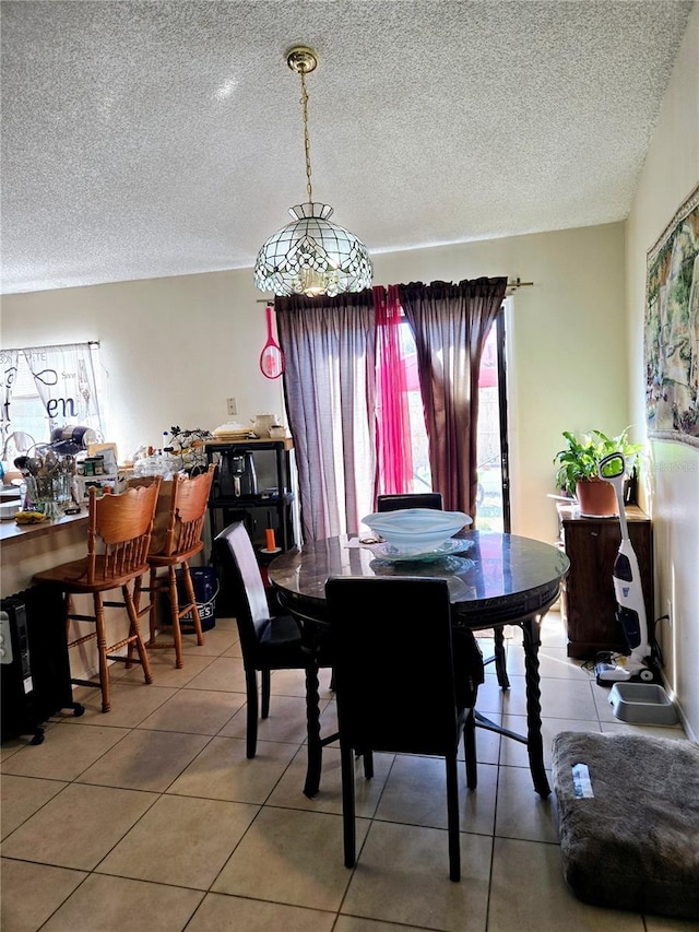 tiled dining room featuring a textured ceiling