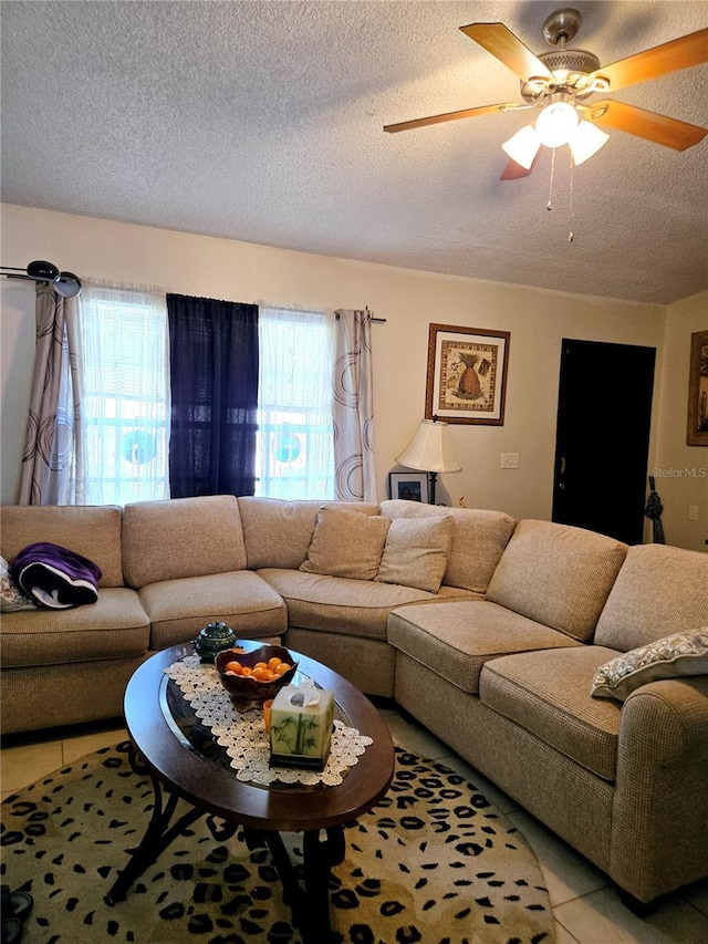 living area with ceiling fan, light tile patterned floors, and a textured ceiling