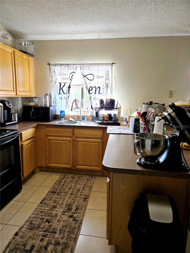 kitchen featuring light tile patterned floors, a textured ceiling, black appliances, and a sink