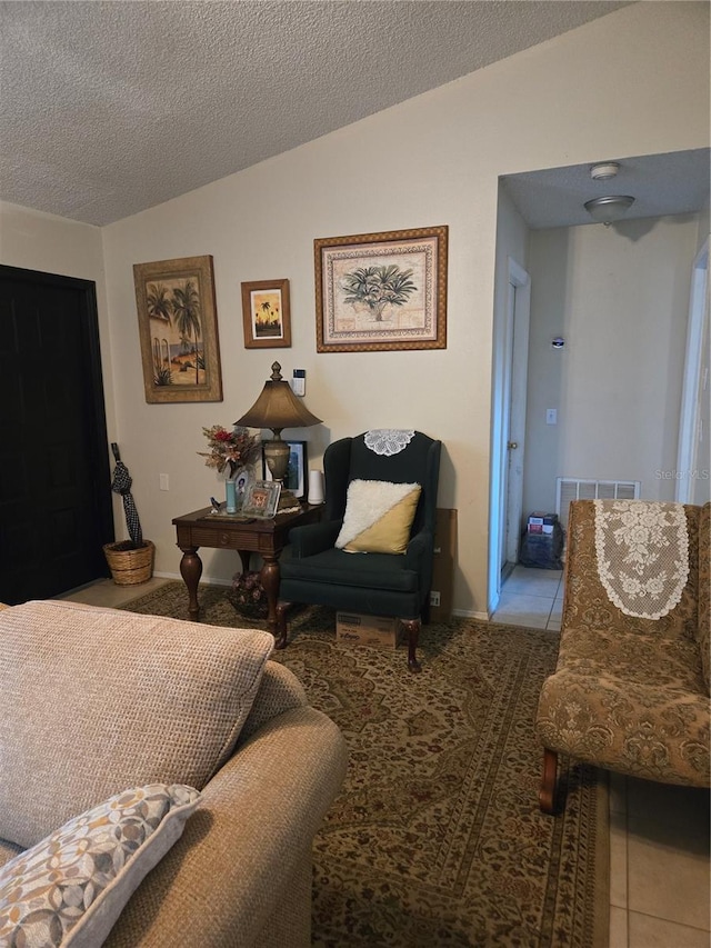 living area featuring tile patterned flooring, visible vents, a textured ceiling, and vaulted ceiling