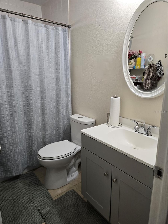 bathroom featuring vanity, a shower with curtain, tile patterned floors, toilet, and a textured wall