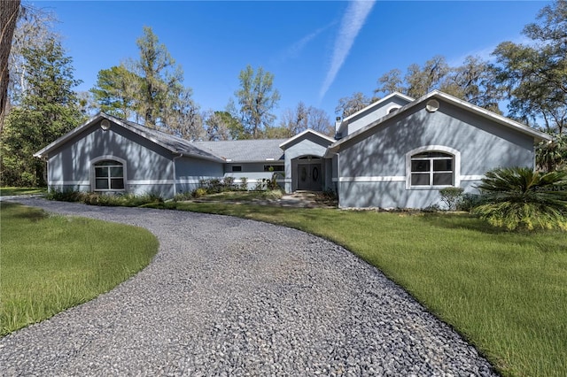 view of front of property with gravel driveway and a front yard