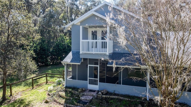 back of property featuring a balcony, a shingled roof, fence, and a sunroom