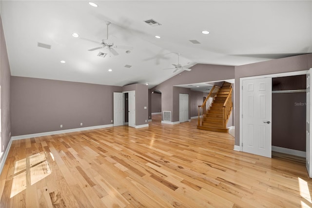 unfurnished living room with lofted ceiling, light wood finished floors, stairway, and visible vents