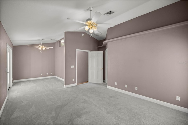 spare room featuring carpet floors, visible vents, a ceiling fan, vaulted ceiling, and baseboards