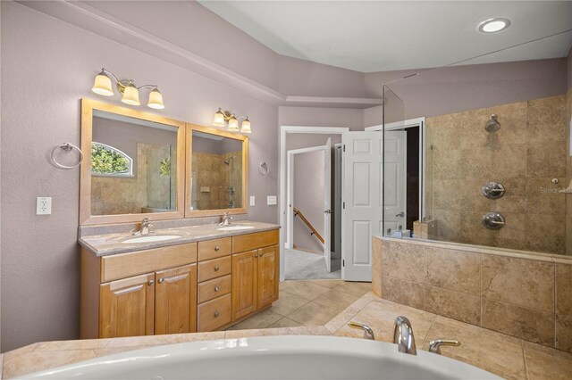 full bath with a tile shower, double vanity, a sink, and a bath