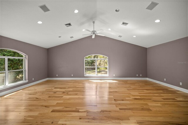 unfurnished room with light wood-style floors, lofted ceiling, visible vents, and baseboards