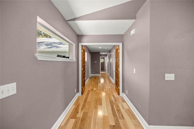 hall featuring light wood-type flooring and baseboards