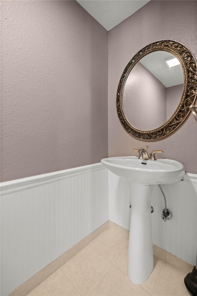 bathroom with a wainscoted wall and tile patterned floors