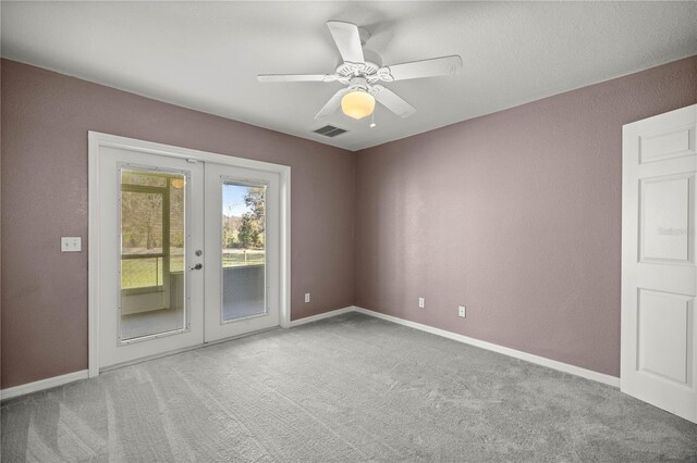 carpeted empty room with visible vents, baseboards, a ceiling fan, and french doors