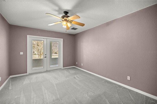 carpeted spare room with french doors, a ceiling fan, visible vents, and baseboards