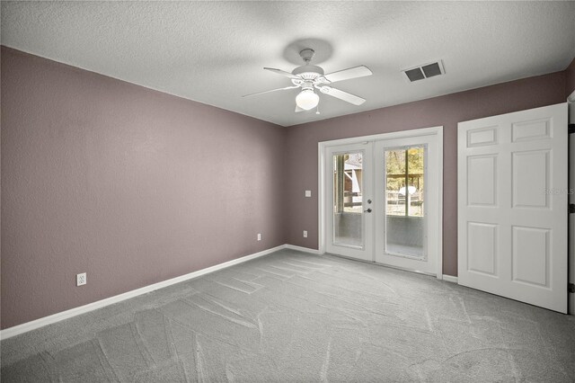 empty room featuring carpet floors, baseboards, a textured ceiling, and french doors