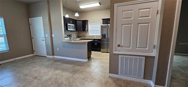 kitchen featuring pendant lighting, stainless steel appliances, visible vents, a sink, and dark cabinets