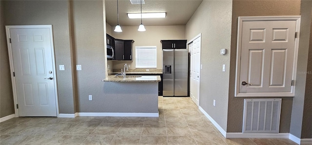 kitchen with stainless steel appliances, a peninsula, a sink, visible vents, and dark cabinetry