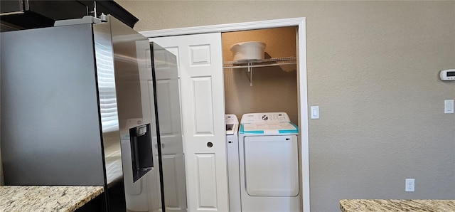 clothes washing area with washer and dryer and a textured wall