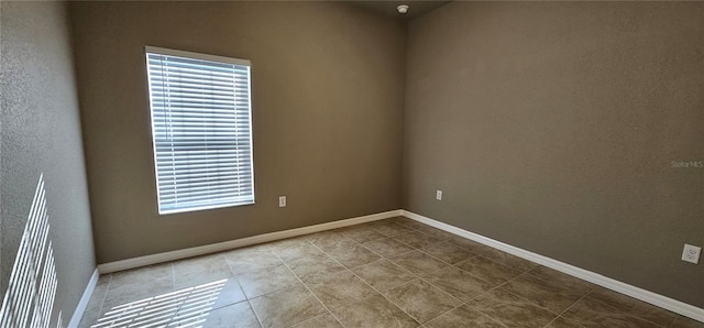 empty room featuring baseboards and tile patterned floors