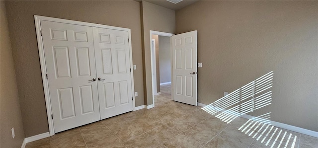 bedroom with a closet, tile patterned floors, and baseboards