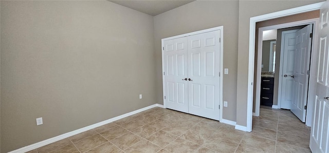 unfurnished bedroom featuring a closet, baseboards, and light tile patterned floors