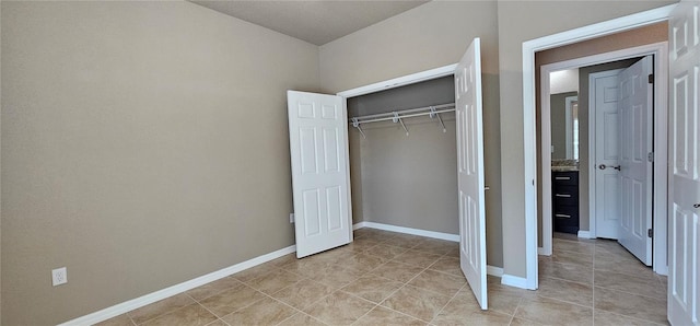 unfurnished bedroom with light tile patterned floors, baseboards, and a closet