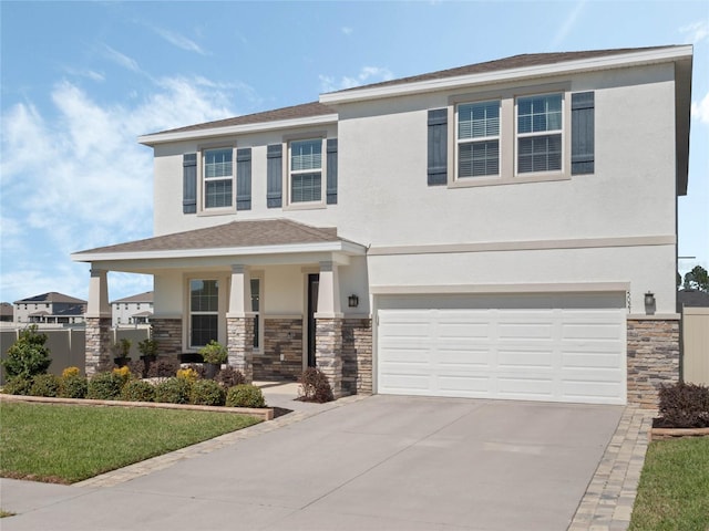 view of front of house with stucco siding, covered porch, a garage, stone siding, and driveway